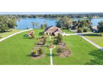 Aerial view of lakefront property with lush landscaping and detached shed at 380 Lakeshore Ave, Umatilla, FL 32784