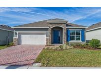 Single-story home with a gray exterior, blue door, and brick driveway at 437 Silver Palm Dr, Haines City, FL 33844