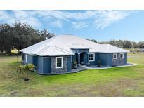 Single-story home with metal roof, stone accents, and a spacious lawn at 2407 Cr 546N, Bushnell, FL 33513