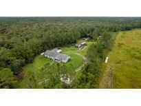 Aerial view of a home on a large lot with mature trees and a pond at 7024 Oil Well Rd, Clermont, FL 34714