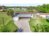 Aerial view of a single-story home with carport, situated on a golf course at 1604 Magnolia Ave, The Villages, FL 32159