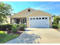 Charming yellow house with white garage door and landscaped front yard at 2434 Soper St, The Villages, FL 32163