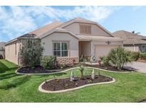 Tan one-story house with landscaped yard and paver driveway at 929 Talapia Loop, The Villages, FL 32162