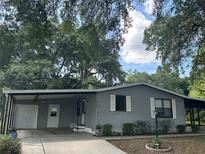 Gray mobile home with carport and landscaping at 1833 Holly Ln, Lady Lake, FL 32159