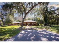 Brick home nestled on a spacious lot with mature trees and a long driveway at 3554 County Road 216, Oxford, FL 34484