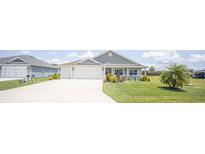 Gray house with two-car garage, landscaping, and a porch at 3532 Thorne Path, Oxford, FL 34484