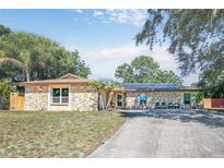 House exterior features stone facade, solar panels, and a paved driveway at 3460 Laurel Dr, Mount Dora, FL 32757