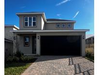 Two-story house with gray siding, black garage door, and paved driveway at 2003 Sunshine Peak Dr, Minneola, FL 34715