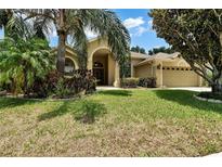 House exterior showcasing a tan house with lush landscaping at 13144 Coldwater Loop, Clermont, FL 34711
