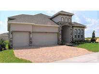 Two-story house with a three-car garage and brick accents at 2311 Juniper Berry Dr, Minneola, FL 34715