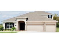 Two-story house with beige exterior, three-car garage, and landscaping at 2368 Juniper Berry Dr, Minneola, FL 34715