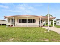 Front view of a single-story manufactured home with a covered carport and well-maintained lawn at 1209 Apache Cir, Tavares, FL 32778