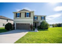 Two story house with a two car garage and landscaped lawn at 11430 Wishing Well Ln, Clermont, FL 34711