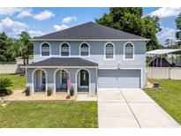 Two-story home with gray siding, arched entryway and landscaping at 7425 Lake Marni Ct, Mount Dora, FL 32757