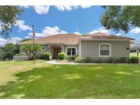 One-story home with a red door and manicured lawn at 5515 Citation Ct, Lady Lake, FL 32159