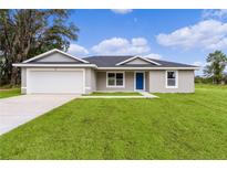 Single story home with attached garage and grassy lawn at 5 Malauka Radial Run Rd, Ocklawaha, FL 32179