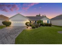 White house with gray roof, paver driveway, and landscaped lawn at 17913 Se 88Th Cascade Ct, The Villages, FL 32162