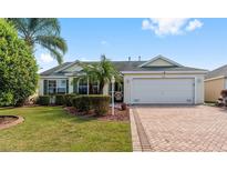 One-story house with yellow exterior, brick driveway, and a manicured lawn at 1683 Moncks Cor, The Villages, FL 32162