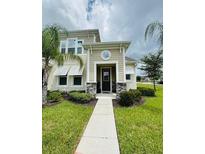 Two-story house with tan siding, stone accents, and a walkway at 2157 Valencia Blossom St, Clermont, FL 34711