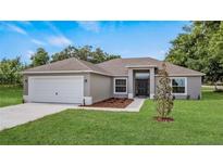 Newly built home with a gray exterior, white garage door, and manicured lawn at 40616 W Fourth Ave, Umatilla, FL 32784