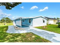 Light blue single-wide manufactured home with carport and landscaped yard at 1520 W Schwartz Blvd, Lady Lake, FL 32159