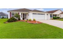 Well-maintained house with a two-car garage and landscaped lawn at 2403 Carriage Hill Way, The Villages, FL 32162