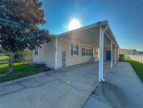 Tan single-wide manufactured home with carport and mature landscaping at 1660 Elkhart Cir, Tavares, FL 32778