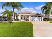 Single-story home with two-car garage, landscaped lawn, and palm trees at 2079 Clarks Hill Way, The Villages, FL 32162