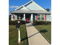 Light blue house with red shutters and a metal roof at 104 Turtle Run, Umatilla, FL 32784