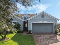 Single-story home with gray exterior, brick driveway, and landscaped yard at 326 Silver Maple Rd, Groveland, FL 34736