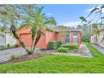 Single story house with orange exterior, paver driveway and landscaping at 540 Grand Canal Dr, Kissimmee, FL 34759