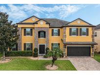 Two-story house with a yellow exterior, brown accents, and a two-car garage at 349 Morning View Dr, Winter Garden, FL 34787