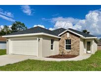 Newly constructed home with a stone facade and attached garage at 15877 Se 98Th Ct, Summerfield, FL 34491