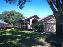 Tan house exterior with a two car garage and landscaping at 8527 Firestone Cir, Clermont, FL 34711