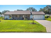 Cute ranch home with a screened porch, landscaped yard, and a two-car garage at 2411 Greenlaw Ct, Leesburg, FL 34788