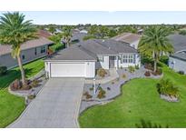 Single-story home with a paved driveway, landscaped yard and two-car garage at 3358 Quail Hollow Ct, The Villages, FL 32163