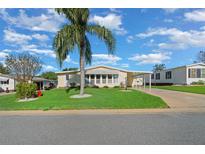 Yellow manufactured home with carport, palm tree, and grassy yard at 1704 Pebble Beach Ln, Lady Lake, FL 32159