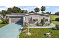 Mobile home with a single-car garage and landscaped yard at 25504 Belle Alliance, Leesburg, FL 34748