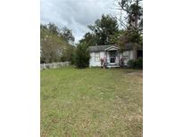 White single story house with American flags, green lawn, and white picket fence at 15518 State Road 19, Groveland, FL 34736