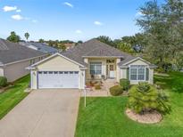 Cute yellow house with a two-car garage and manicured lawn at 2234 Westchester Way, The Villages, FL 32162