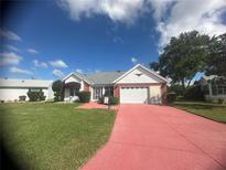 Brick ranch house with two-car garage and landscaped yard at 956 Chula Ct, The Villages, FL 32159