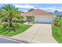 Single-story house with driveway, palm tree, and well-maintained lawn at 1514 Fenimore Ln, The Villages, FL 32162