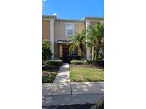 Tan two-story townhome with dark brown door, landscaping, and walkway at 652 Chelsea Dr, Davenport, FL 33897