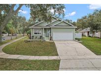 Green house exterior with driveway, landscaping, and a peaceful street view at 1101 Lake Elsie Dr, Tavares, FL 32778