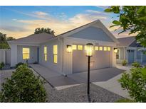 Charming one-story house with gray garage door, light blue accents and landscaping at 5238 Dalessandro Rd, The Villages, FL 32163