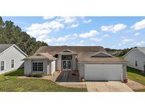Single-story house with attached garage and landscaped yard at 25114 Meriweather Rd, Leesburg, FL 34748