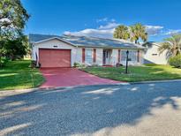 House exterior featuring a peach-colored garage door and red driveway at 5006 El Destino Dr, Leesburg, FL 34748