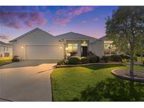 Single-story home with a white exterior, two-car garage, and landscaped yard at 1006 Sayle St, The Villages, FL 32162