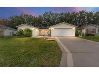 Inviting yellow home with a 2-car garage and well-manicured lawn at 1612 Staunton St, The Villages, FL 32162