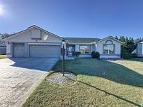 Single-story house with gray siding, two-car garage, and well-manicured lawn at 4634 Summerbridge Cir, Leesburg, FL 34748